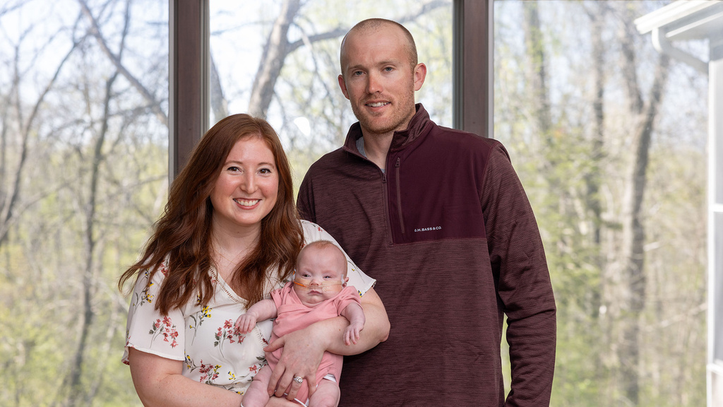 parents holding their infant daughter at their home