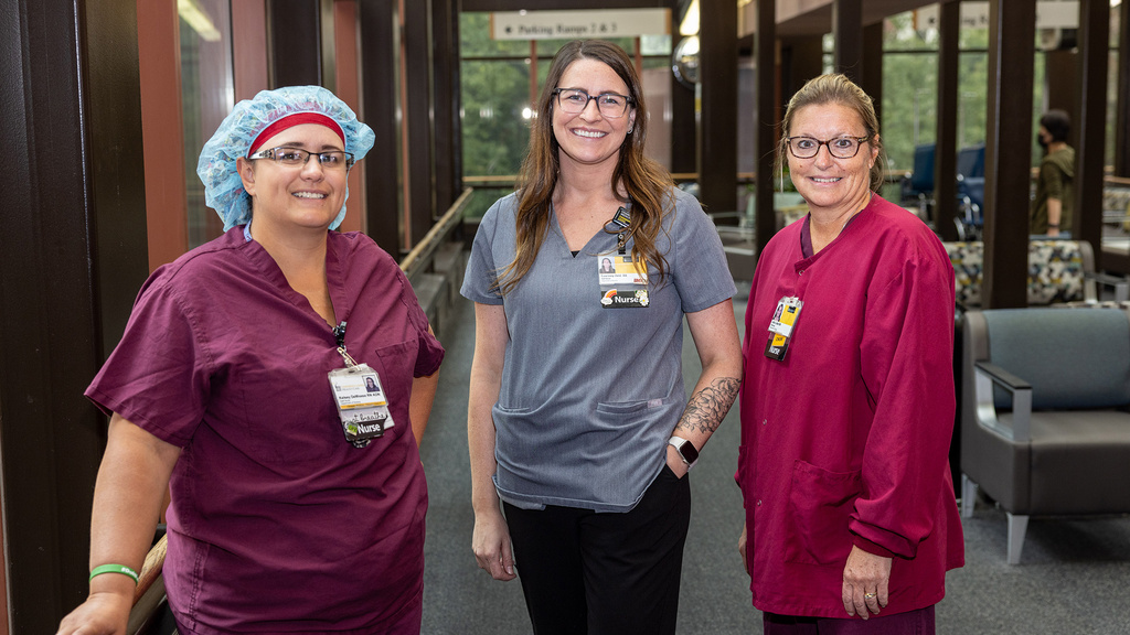 Three nurses standing in a lobby smiling