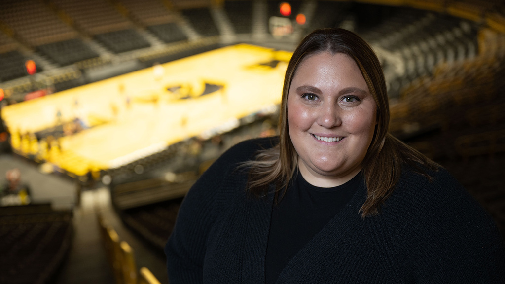 A woman smiling for a photo with a basketball court in the background