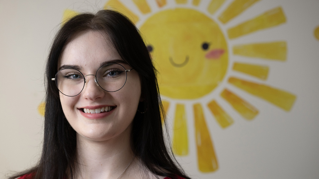 A woman standing in front of a mural of the sun smiling