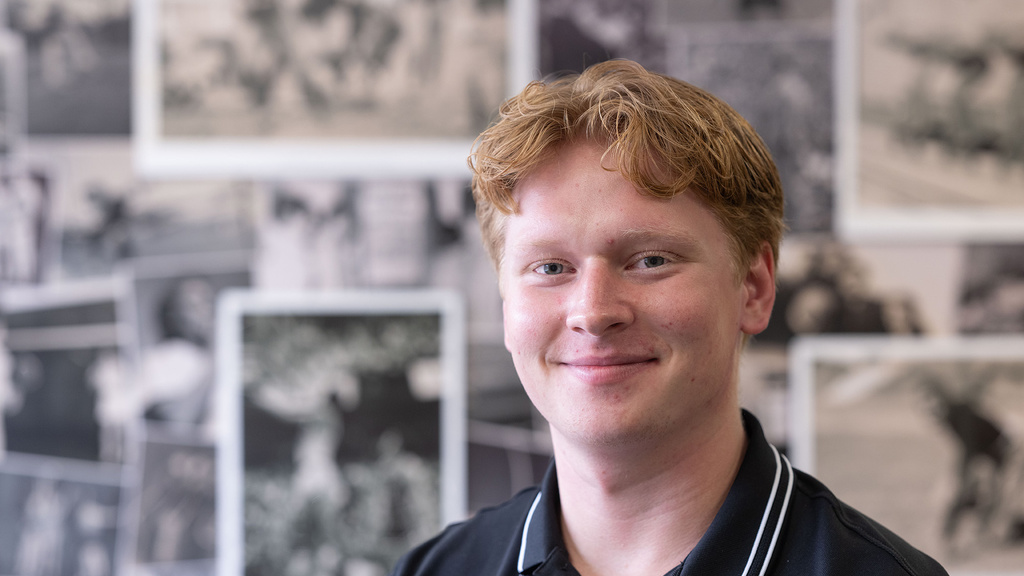 A man posing for a portrait in front of a photo wall