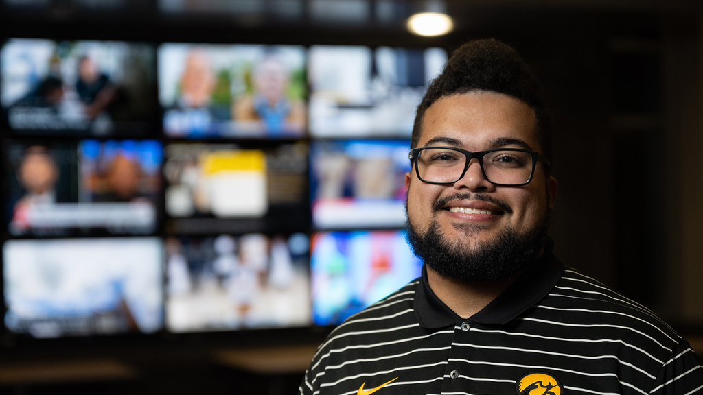 A man standing in front of multiple screens posing for a portrait