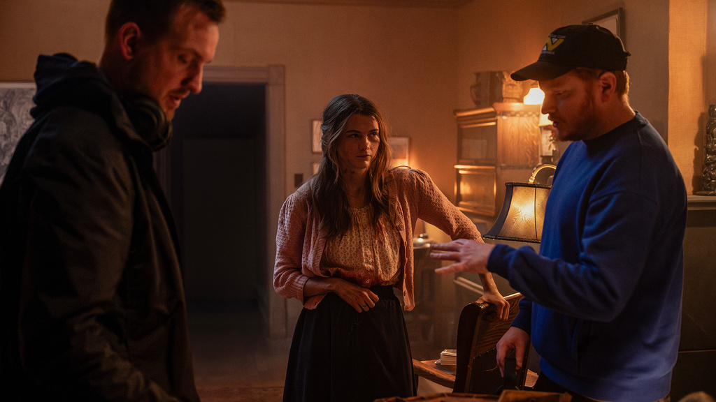 Two men directing an actress in a living room set