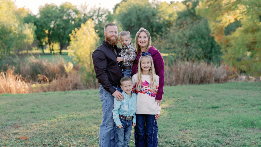 A smiling family of five standing in a field