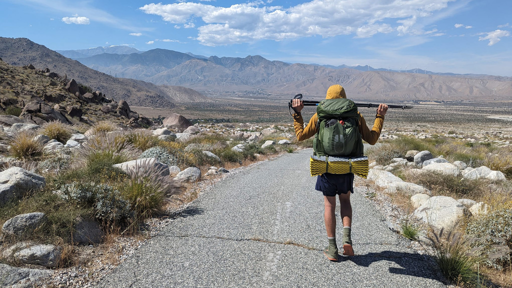 a man walking on a path with mountains visible in the distance