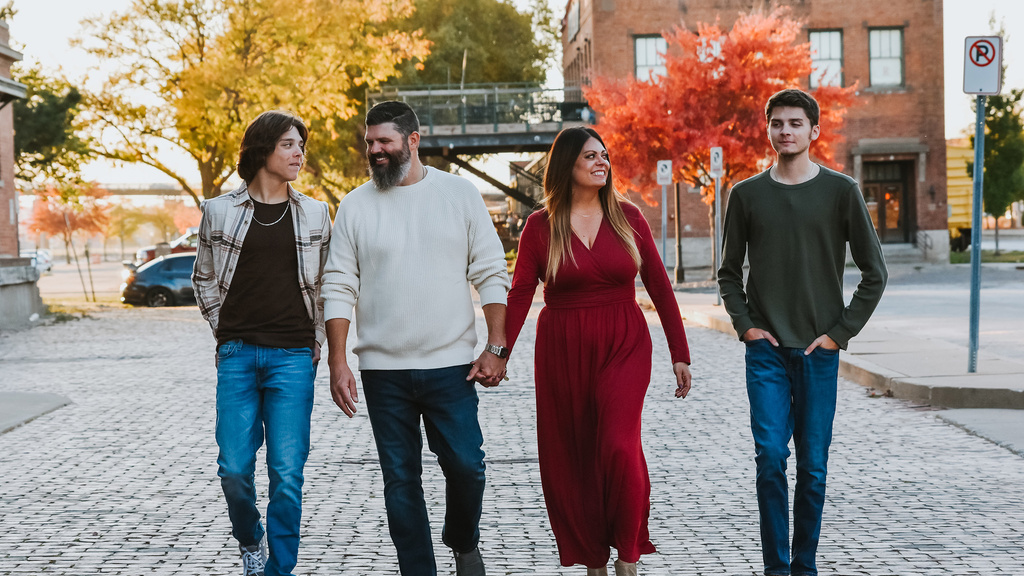 A family of four smiling walking down a stone alley