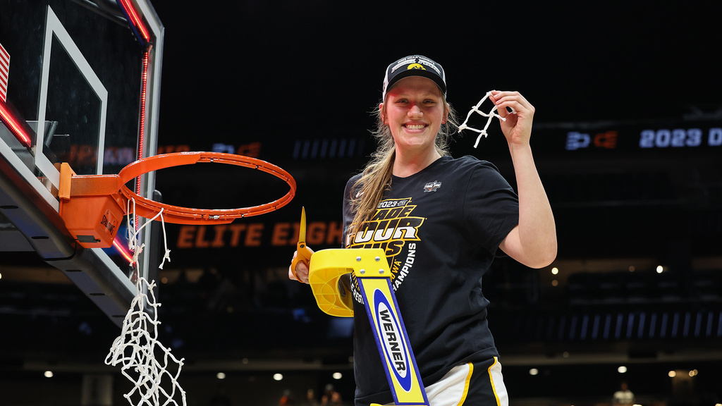 A basketball player holding up a piece of the net she just cut down and smiling