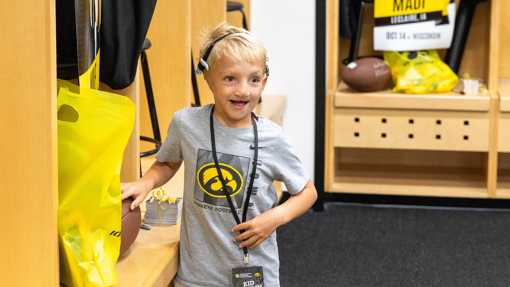 A young boy standing in a locker room and smiling