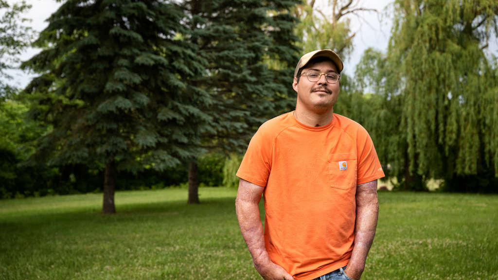 A man standing in a field with trees behind him