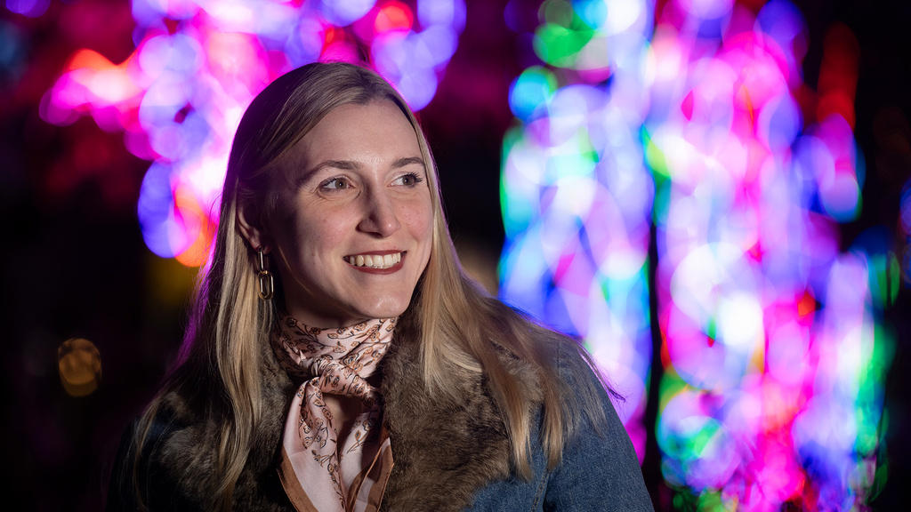 A woman smiling with many different colored lights behind her