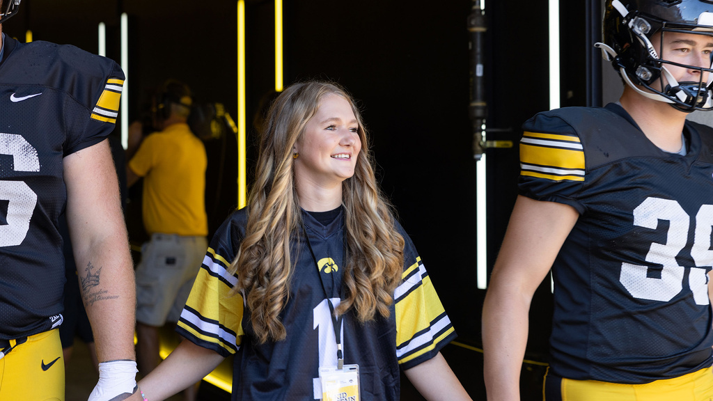 A girl holding hands with two football players