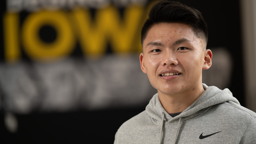 A man smiling with an IOWA poster behind him