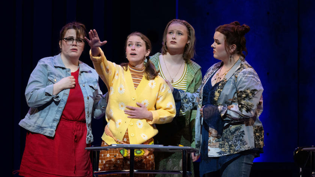 A group of four performers on stage looking over the crowd