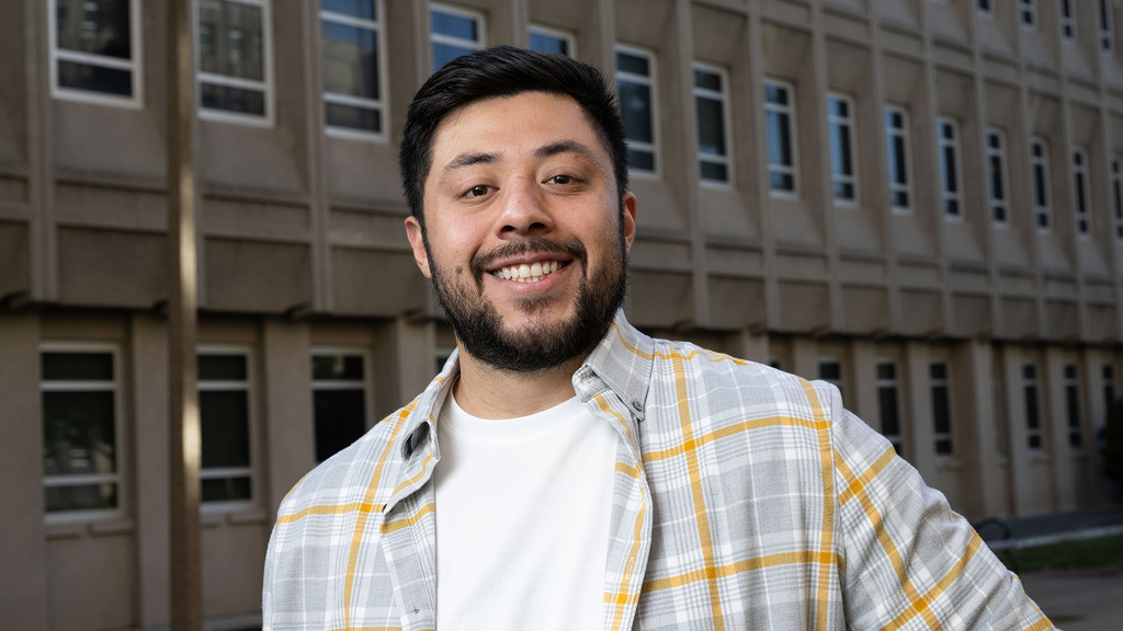A man standing in front of a tall building while smiling