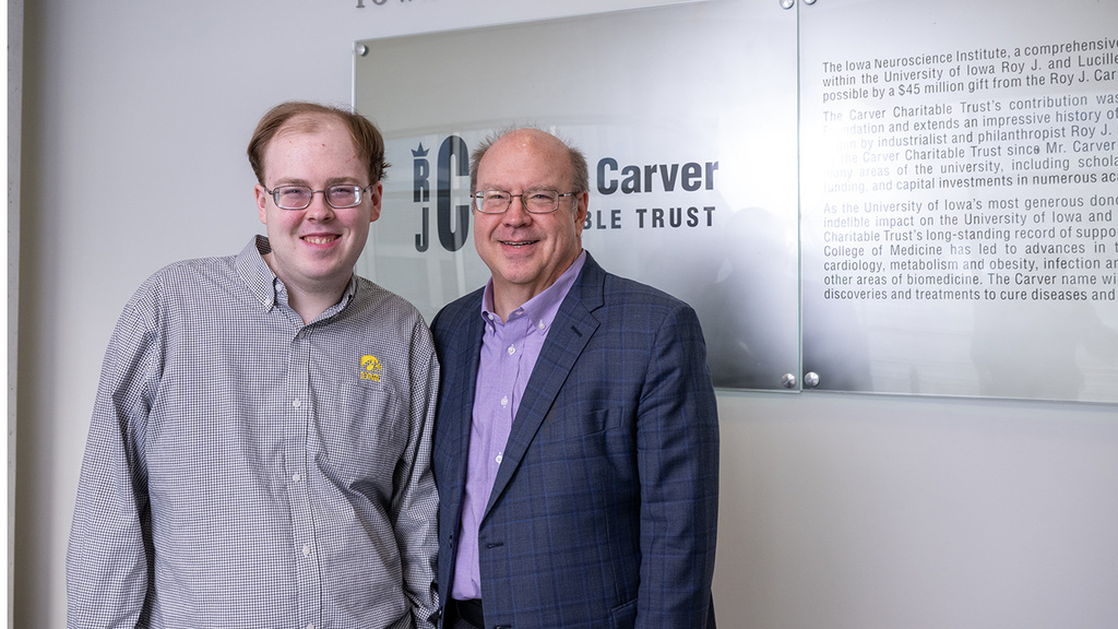 a young man and his father stand together for a portrait