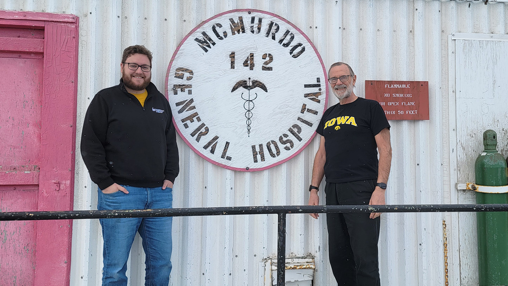 Two men standing outside of a hospital smiling