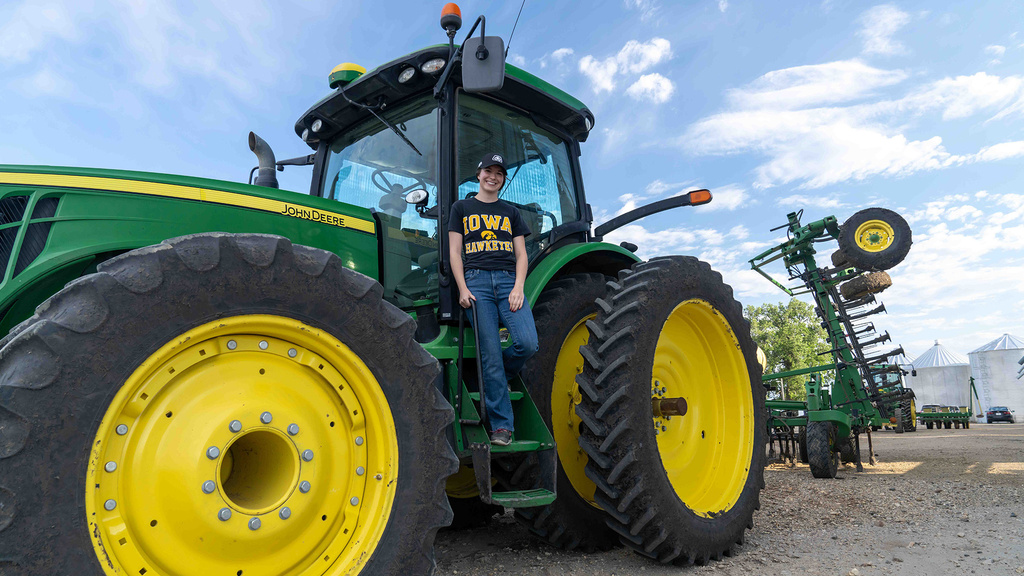 A woman standing on the ladder to a tractor