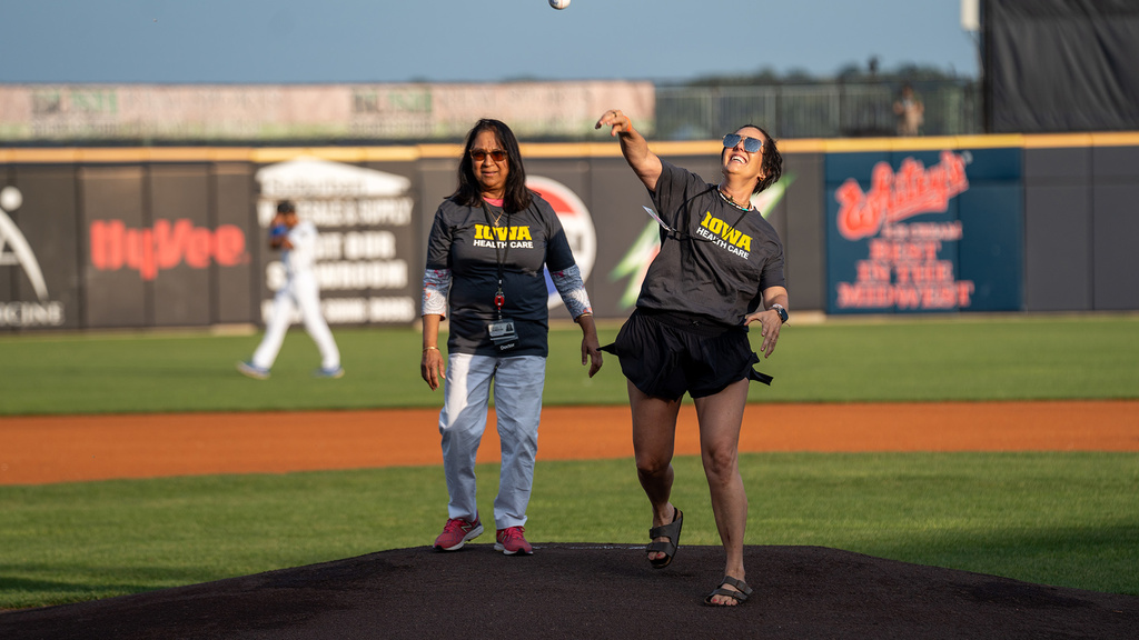 Two people standing on a pitcher's mound as one of them throws a ball