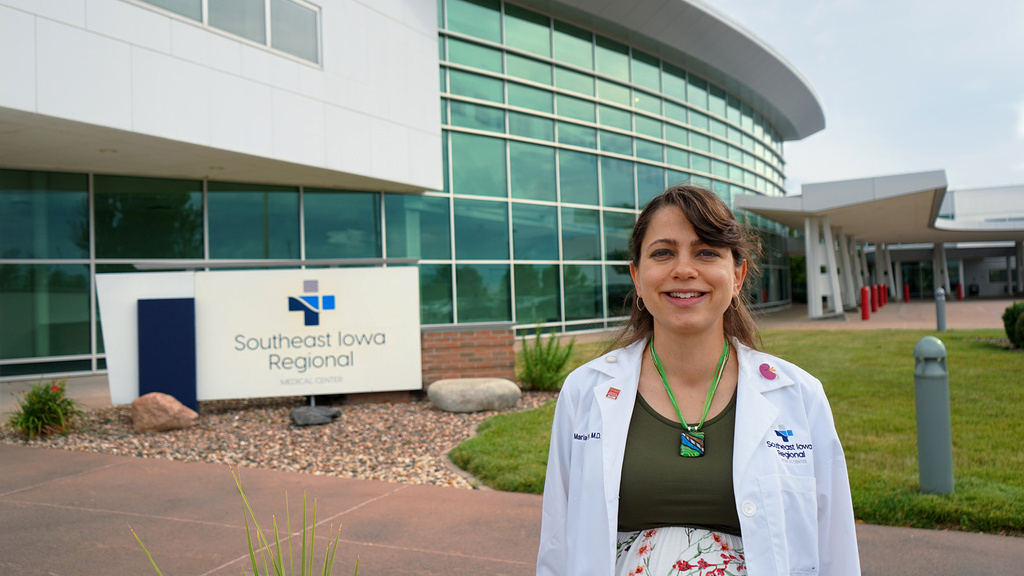 A doctor standing outside a hospital while smiling