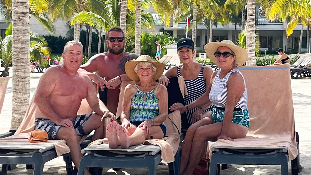 A group of people siting on the beach and smiling