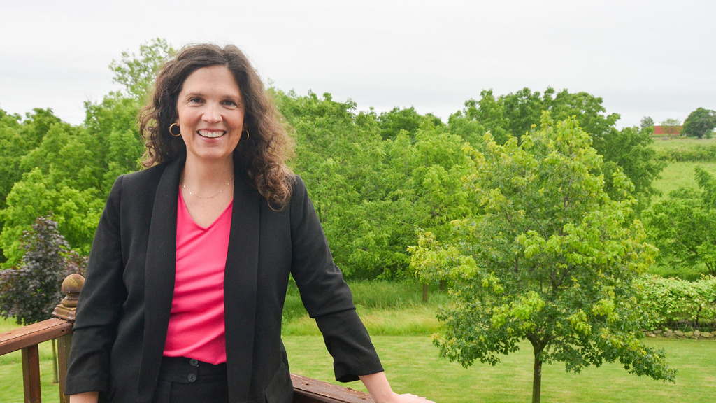 A woman standing on a balcony with a forest in the back