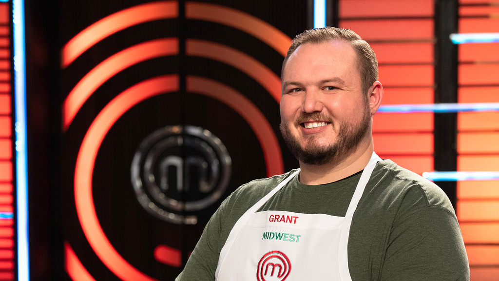 A photo of a man smiling dressed in an apron