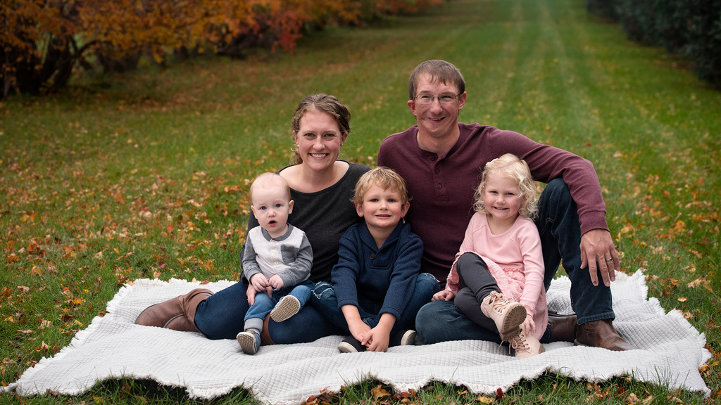 A family of five sitting outside on a blanket