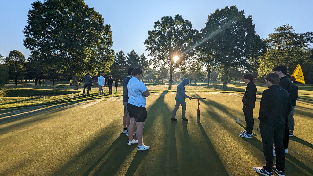 A group of people standing on a putting green