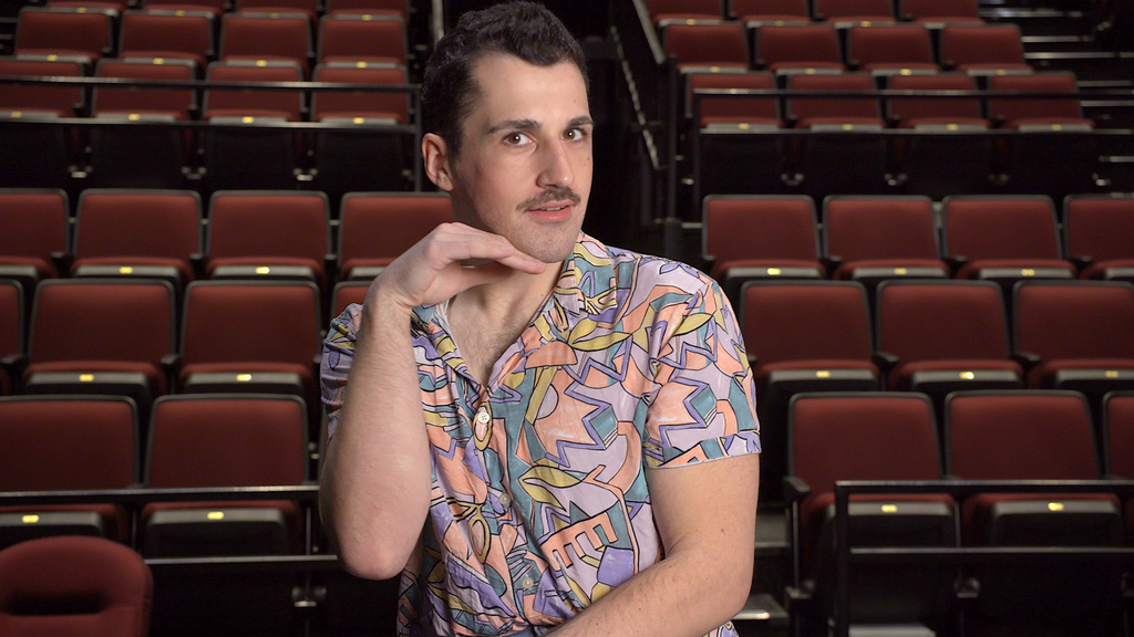 A person sitting in an empty theater with a hand under their jaw