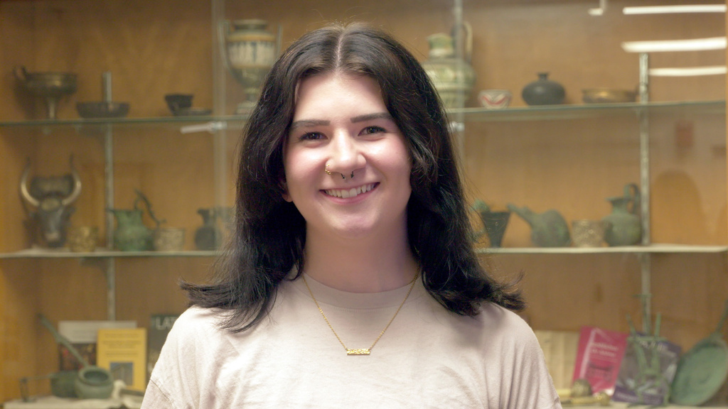 A woman standing in front of a case full of pottery