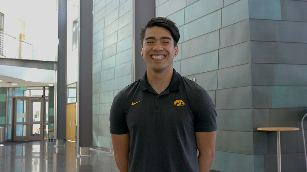 A man standing with his arms behind his back and smiling