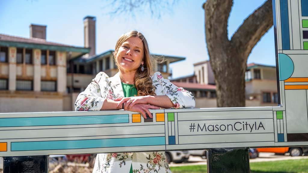 A woman leaning on a sign and smiling