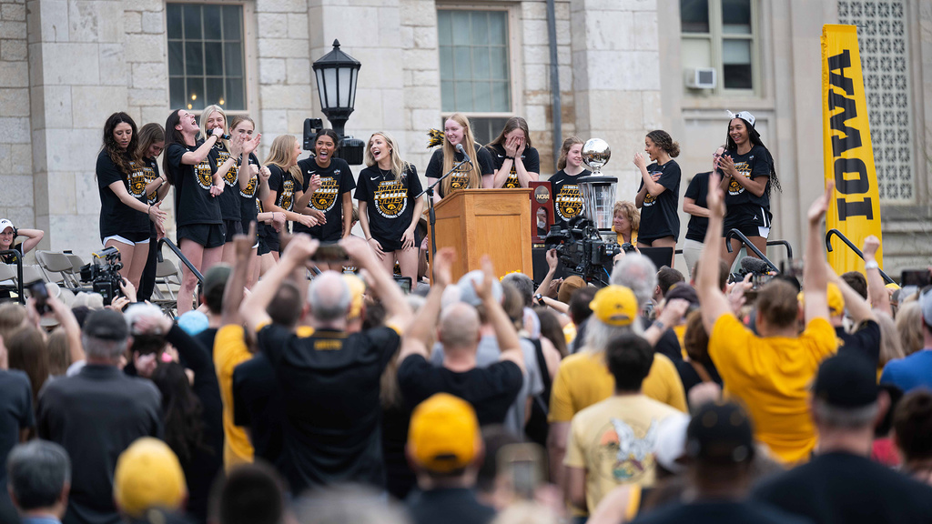 A group of peple on stage with a cheering crowd below them