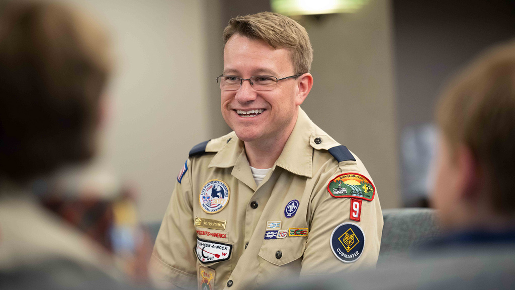 A man smiling talking to a group of kids