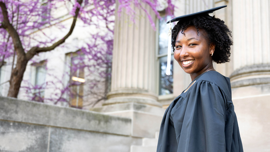 A woman standing on a set of steps in a cap and gown