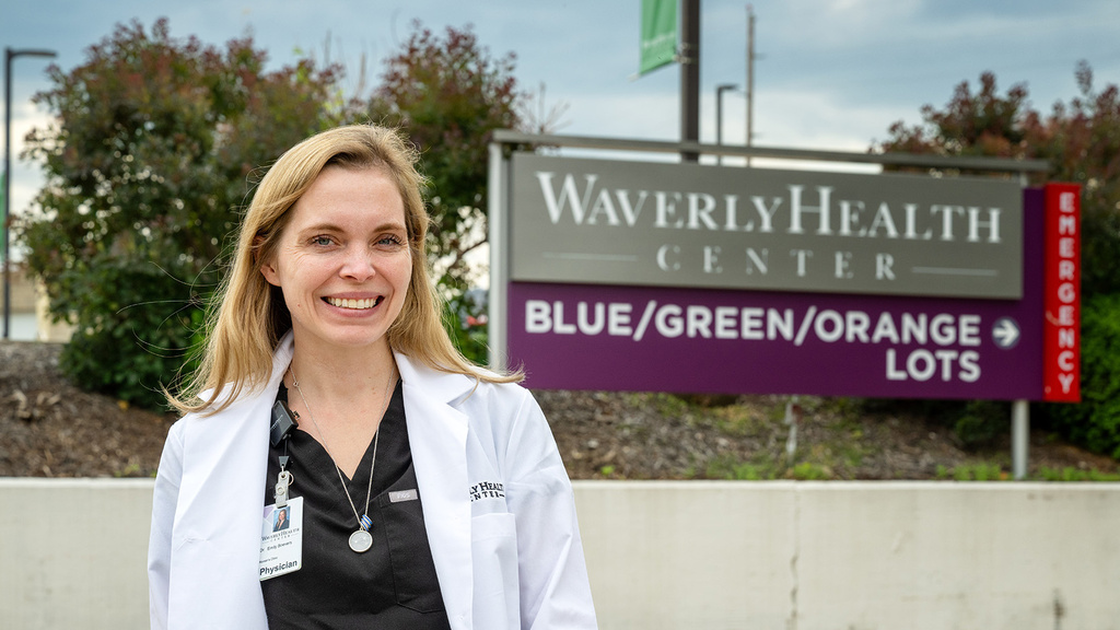 A woman smiling with a healthcare sign in the background