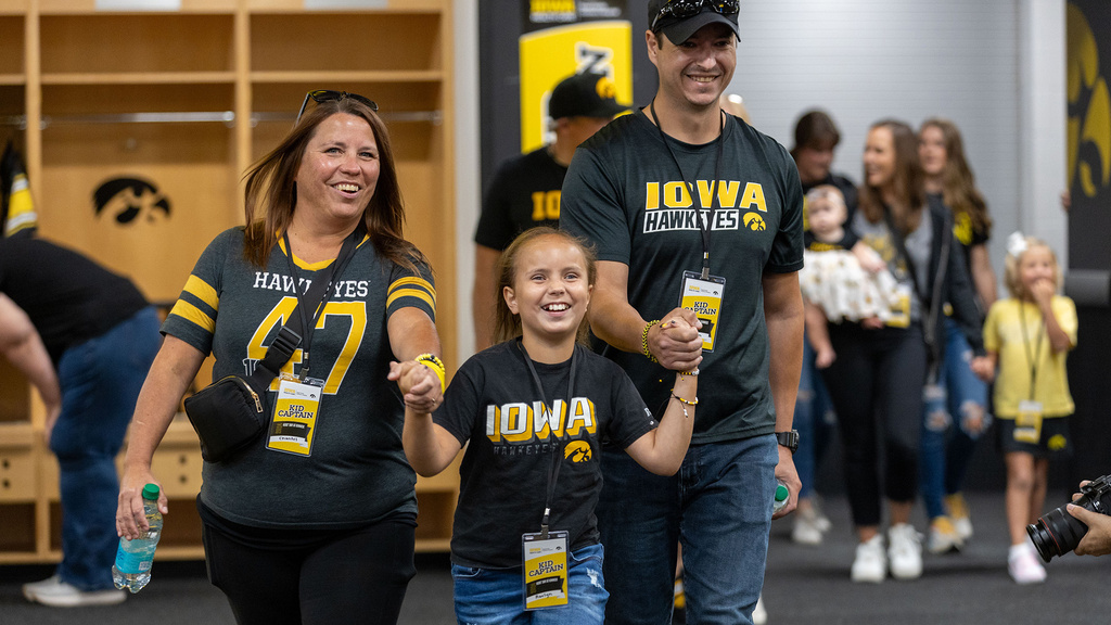 A young girl walking with her parents holding her hand