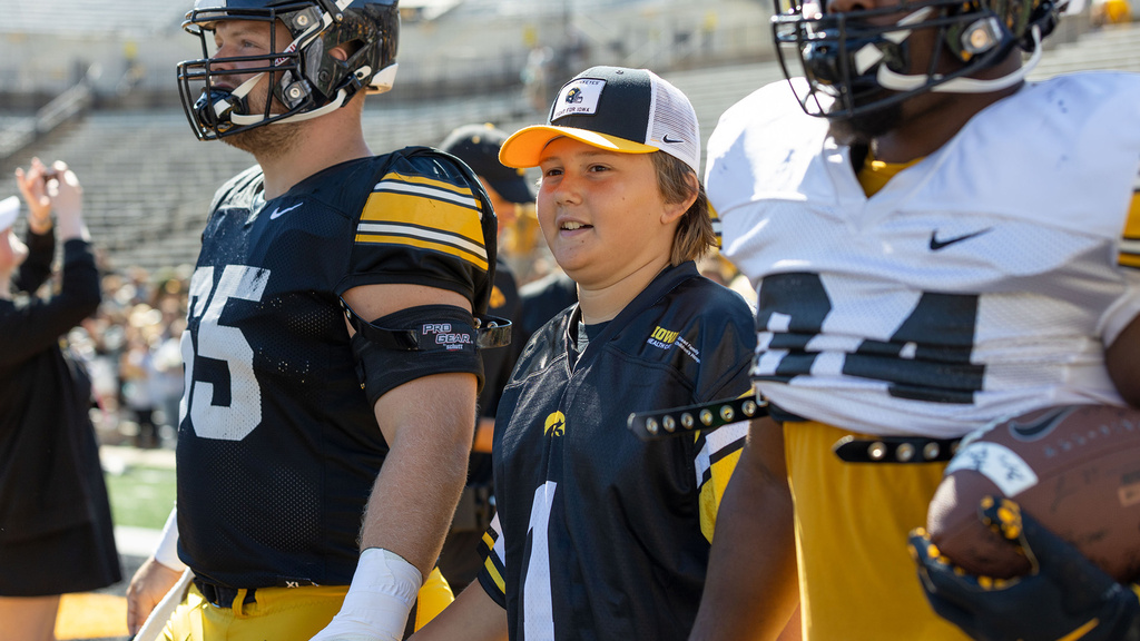 A boy standing between two football players