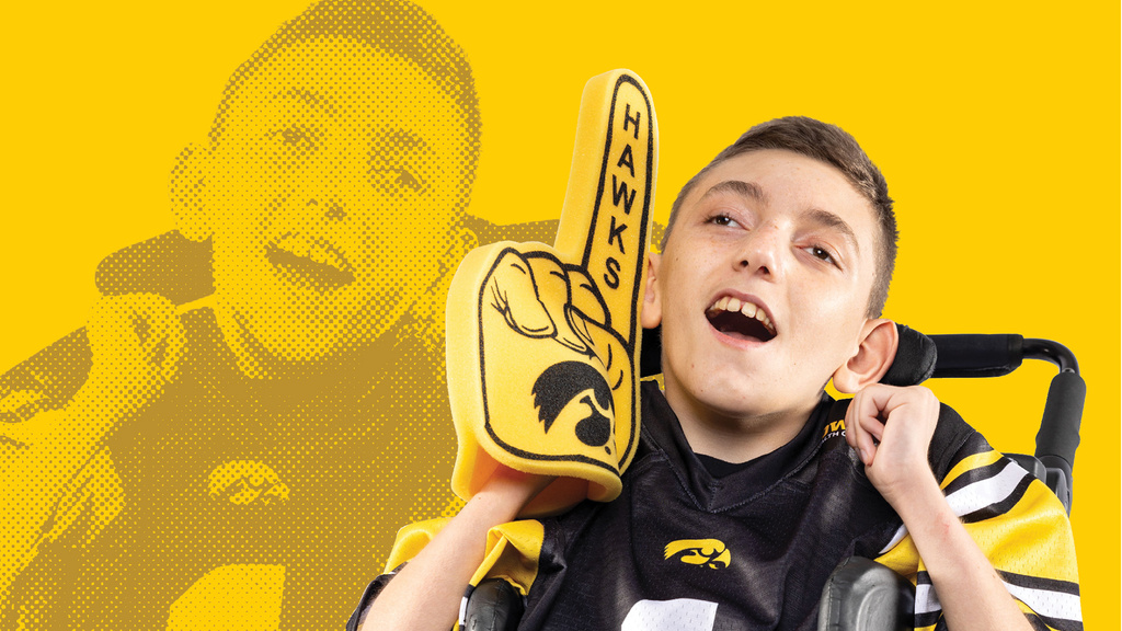 A boy sitting in a wheel chair with a foam finger