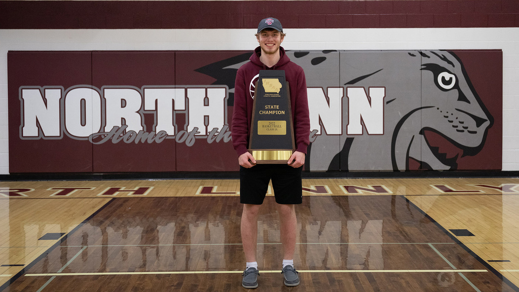 a high school student standing in a gymnasium holding a trophy