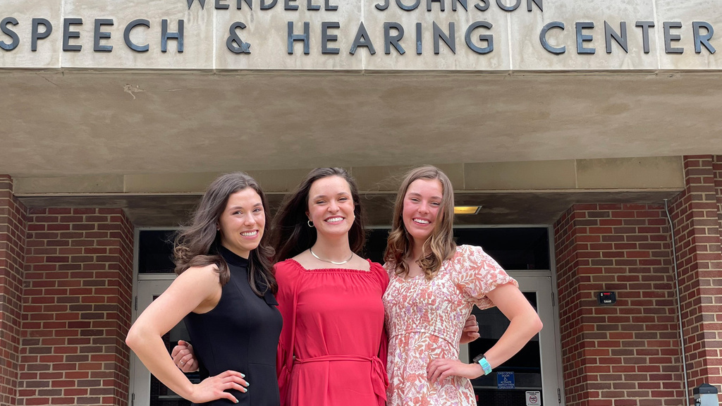 Three women standing together outside a hearing center