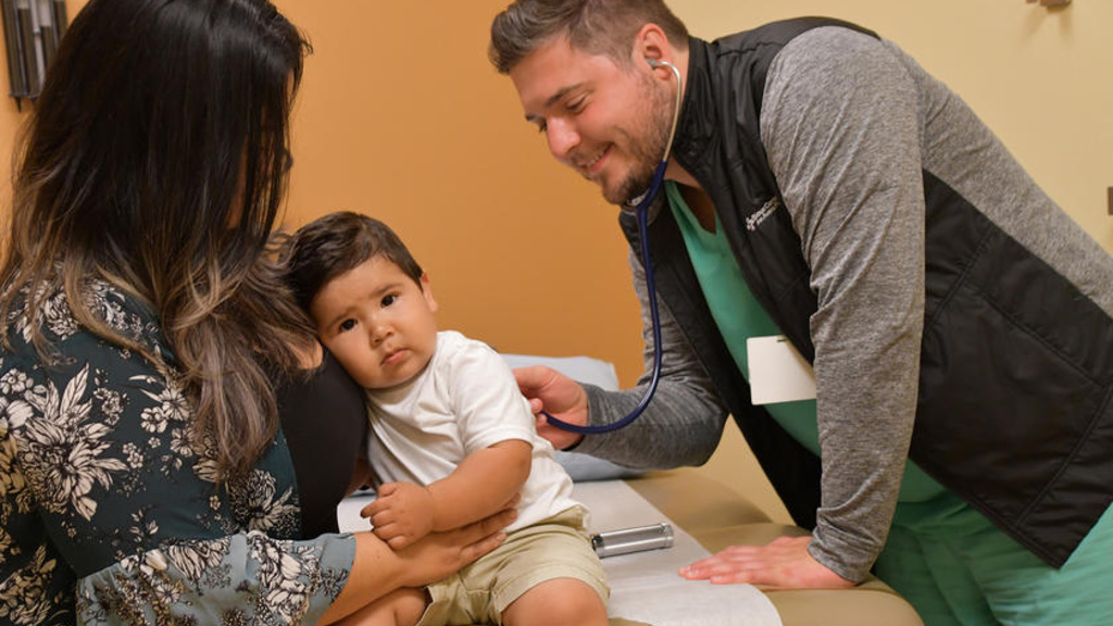 A young child leaning on their mother at the doctors office