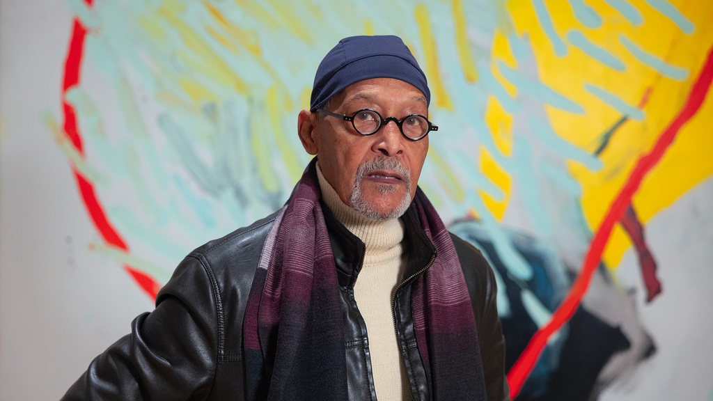 A man standing in front of a colorful mural