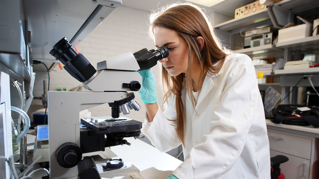 a woman in a lab using a microscope