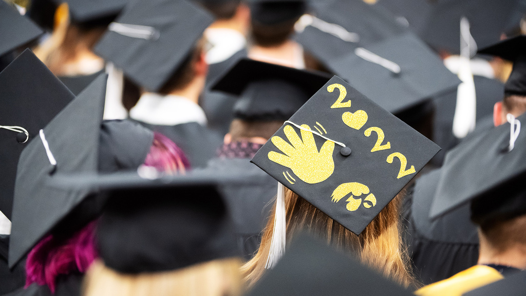 a scene from graduation, where one grad's cap features a waving hand and the year 2022 on it
