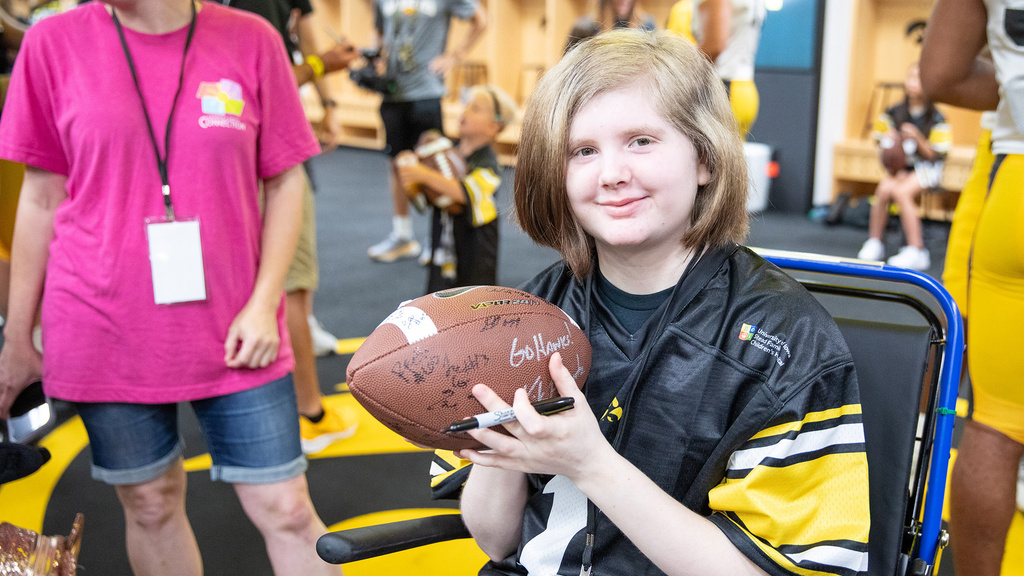 A girl holding a football with different signatures on it