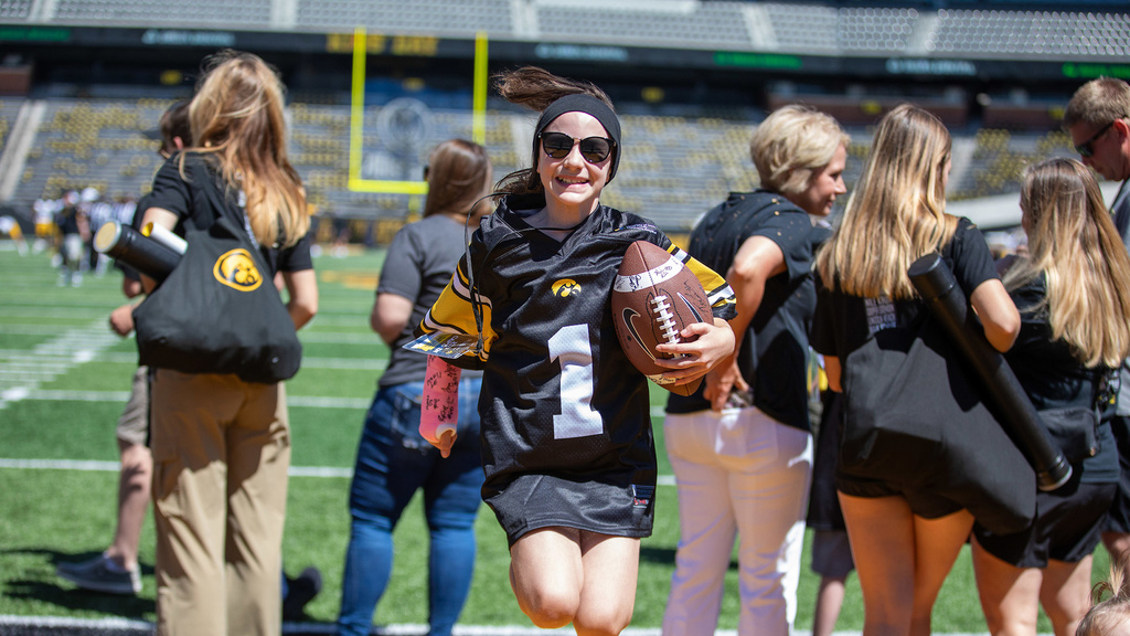 A girl jumping while holding a football