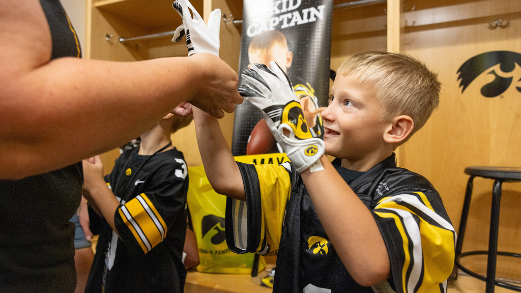 A boy in a locker room putting on gloves