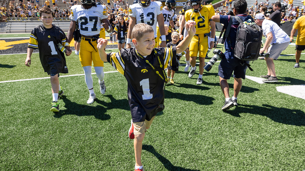 A young boy running out onto a fooball field