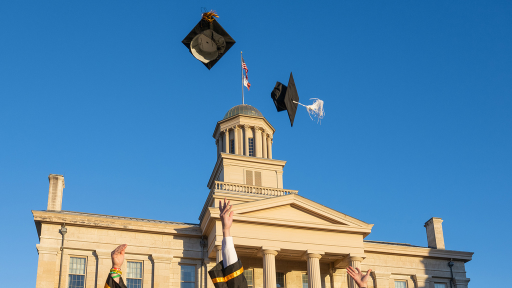grads standing near old capitol, throwing caps in the air